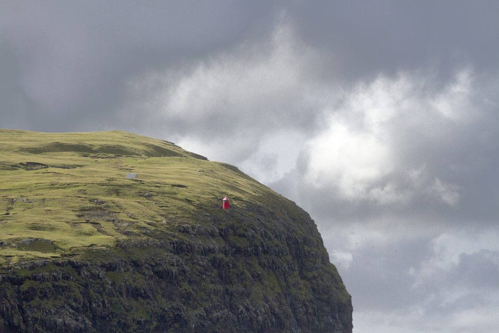 A lighthouse on top of a cliff in the Faroe Islands. Discover the best things to do in the Faroe Islands.