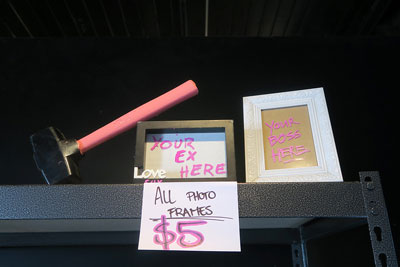 A pink handled axe at Melbourne Break Room, sitting next to two picture frames. One reads 'Your ex here' the other 'Your boss here' and they're priced at $5.