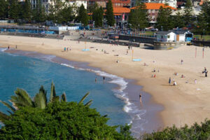 View of Coogee Beach in Sydney, where people mill about by the ocean in May. Discover when is the best time to visit Australia.