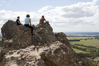 People sit astride a craggy rock formation in Victoria known as Hanging Rock. This is one of the most popular day hikes near Melbourne.