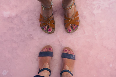 Two feet in sandals standing in Lake Tyrrell in west Victoria. Discover this and other pink lakes of Victoria.